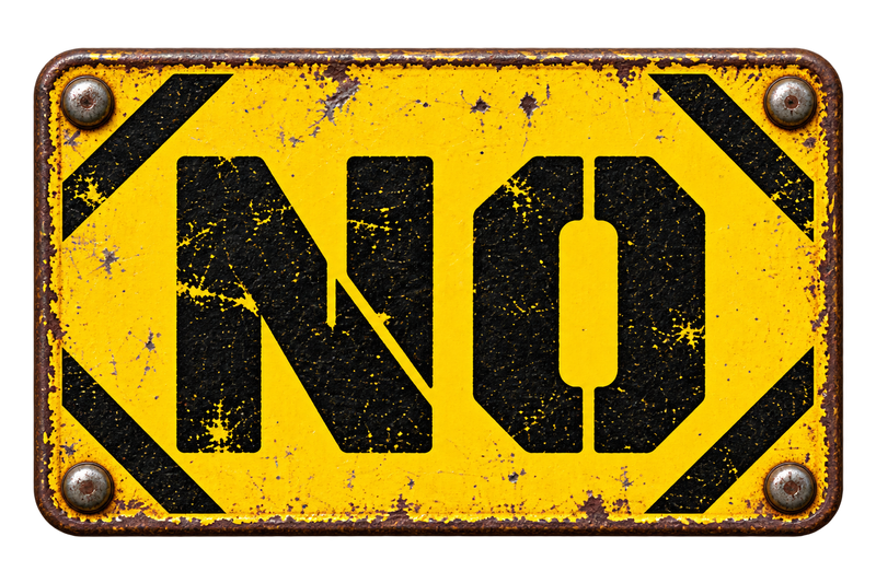 NO in black stencil type on a distressed yellow industrial sign.